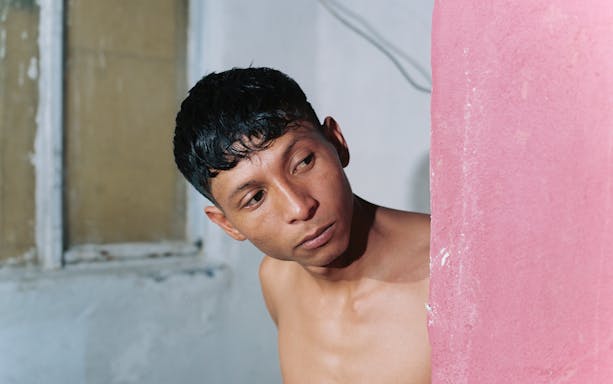 Man peering from behind a pink wall at KBr Fundación MAPFRE Barcelona.