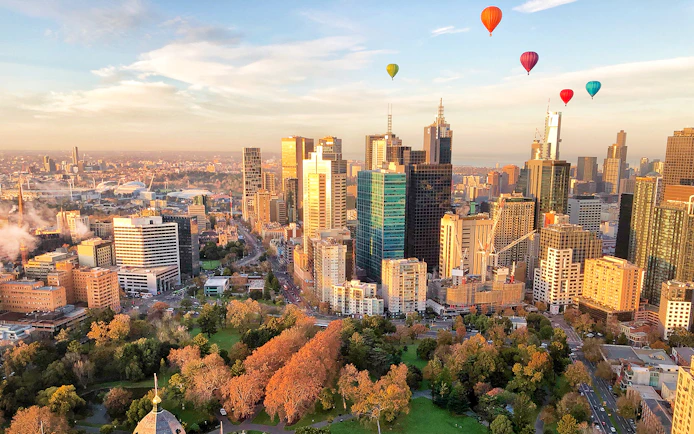 Hot air balloons over Melbourne skyline at sunrise.