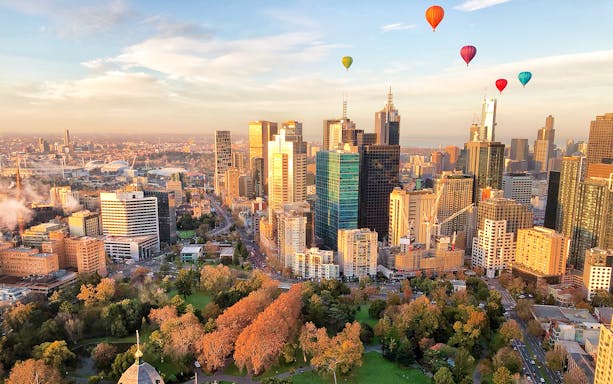Hot air balloons over Melbourne skyline at sunrise.