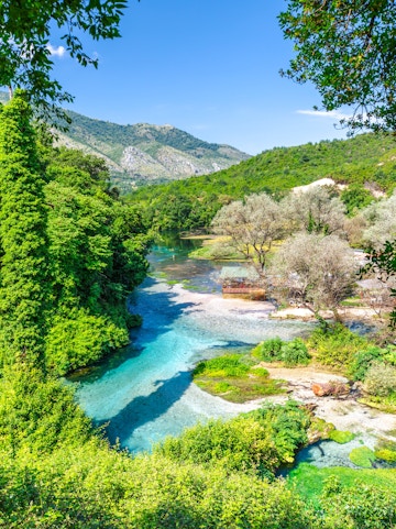Blue Eye water spring in Albania with clear turquoise water and lush green surroundings.