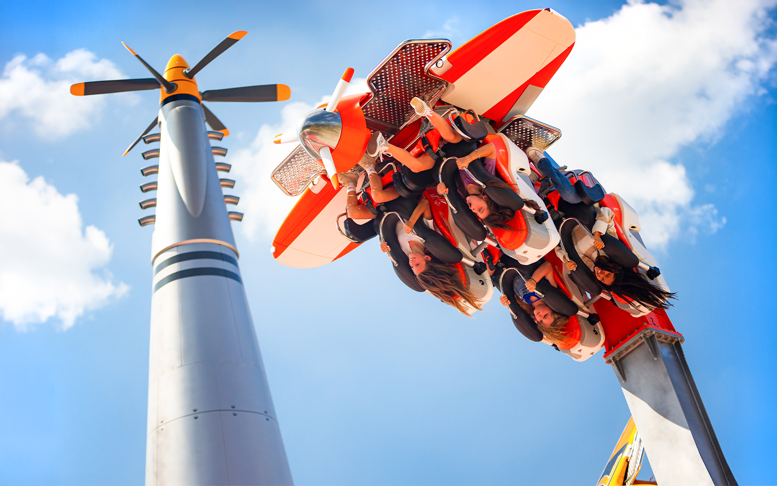 Six Flags Carowinds Air Racers ride with passengers upside down against blue sky.