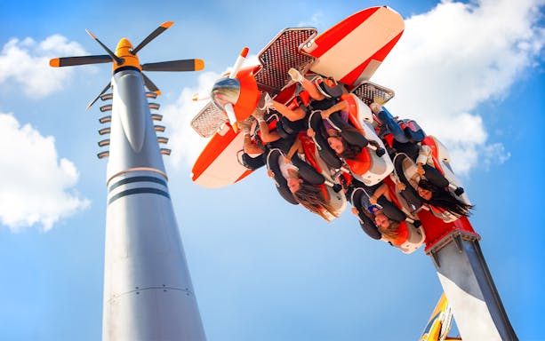 Six Flags Carowinds Air Racers ride with passengers upside down against blue sky.