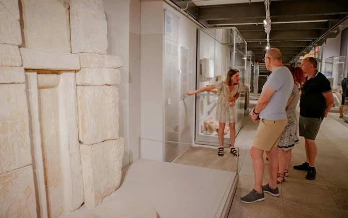 Guide explaining ancient artifacts to visitors at the Egyptian Museum in Turin.