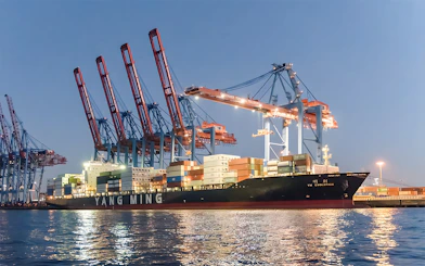 Container ship docked at Grand Harbor under evening lights during 1.5h cruise.