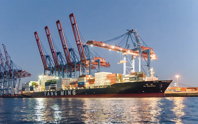 Container ship docked at Grand Harbor under evening lights during 1.5h cruise.