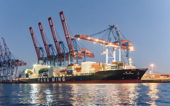 Container ship docked at Grand Harbor under evening lights during 1.5h cruise.