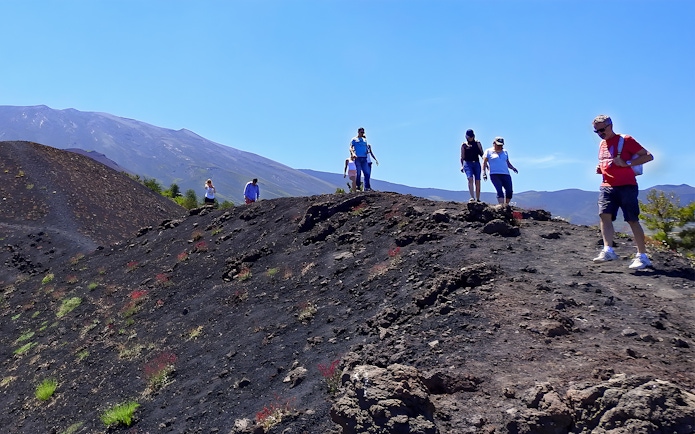 Hikers exploring volcanic terrain on Mount Etna, Sicily.