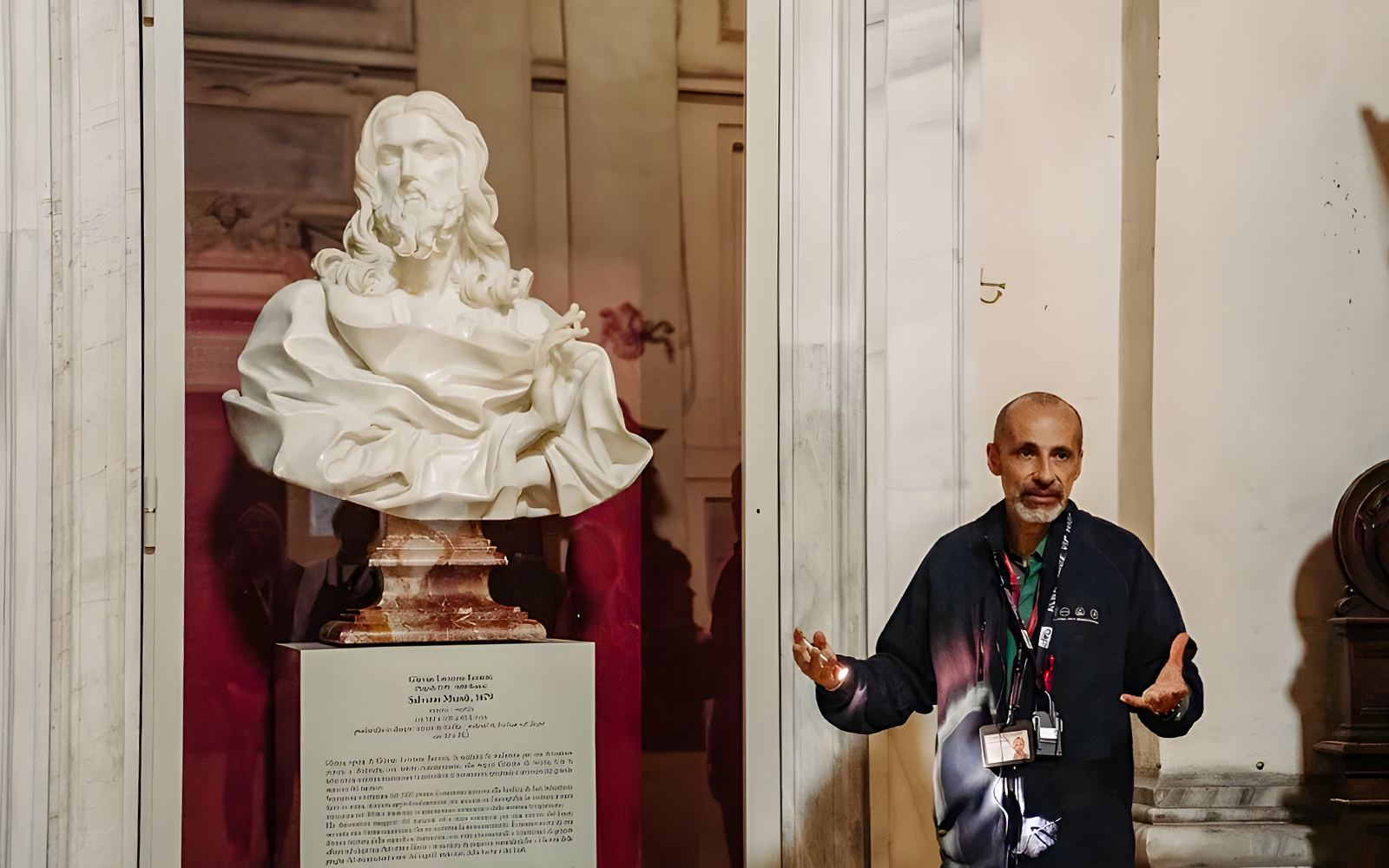 Guide explaining a marble bust in the Basilica of San Nicola during a Roman Catacombs tour.