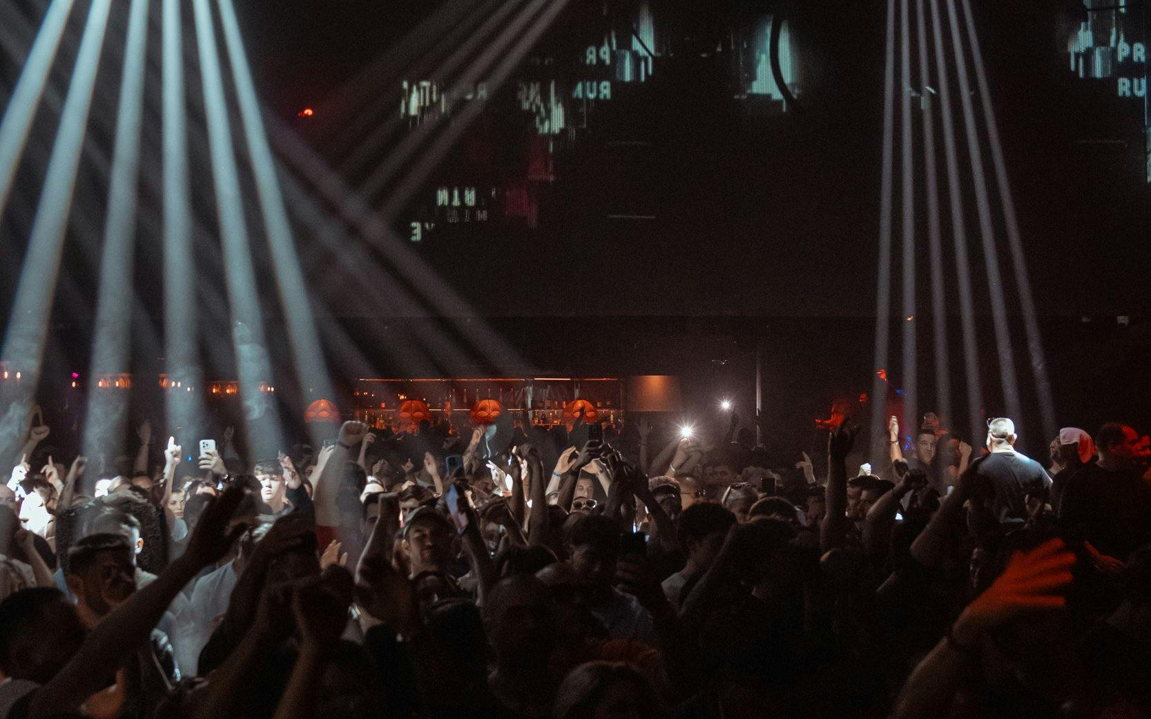 DJ performing at La Troya Club Chinois, Ibiza with crowd dancing under lights.