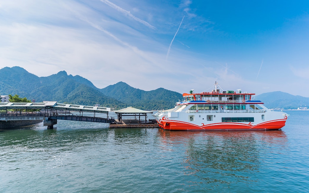 Ferry docked at Miyajima Island with mountains in the background, part of Hiroshima tour.