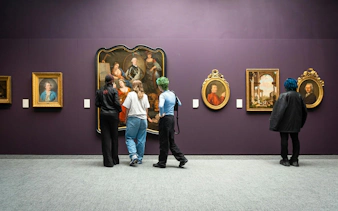 Visitors viewing classic paintings at Groeningemuseum, Bruges.