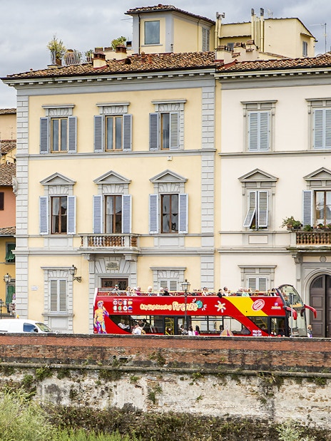 HOHO tour bus passing by historic buildings near Hotel Embassy, Florence.