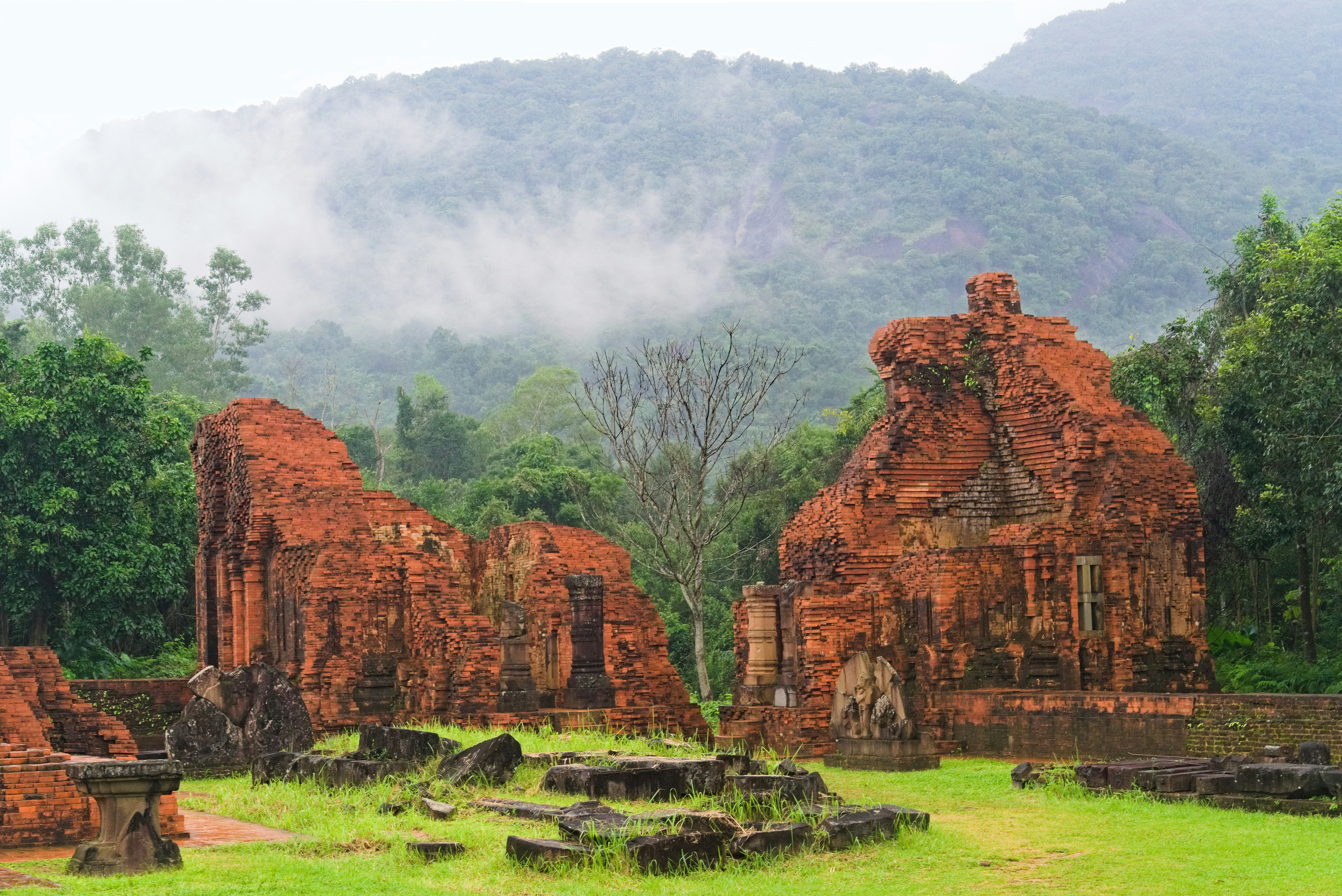 Ancient brick ruins of Champa civilization at My Son Sanctuary, Vietnam, surrounded by lush greenery.