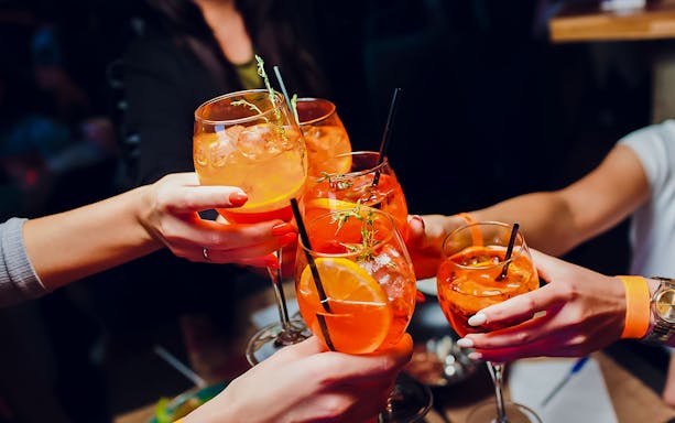 People toasting with Aperol Spritz at Illy Caffè, St. Mark's Square, Venice.