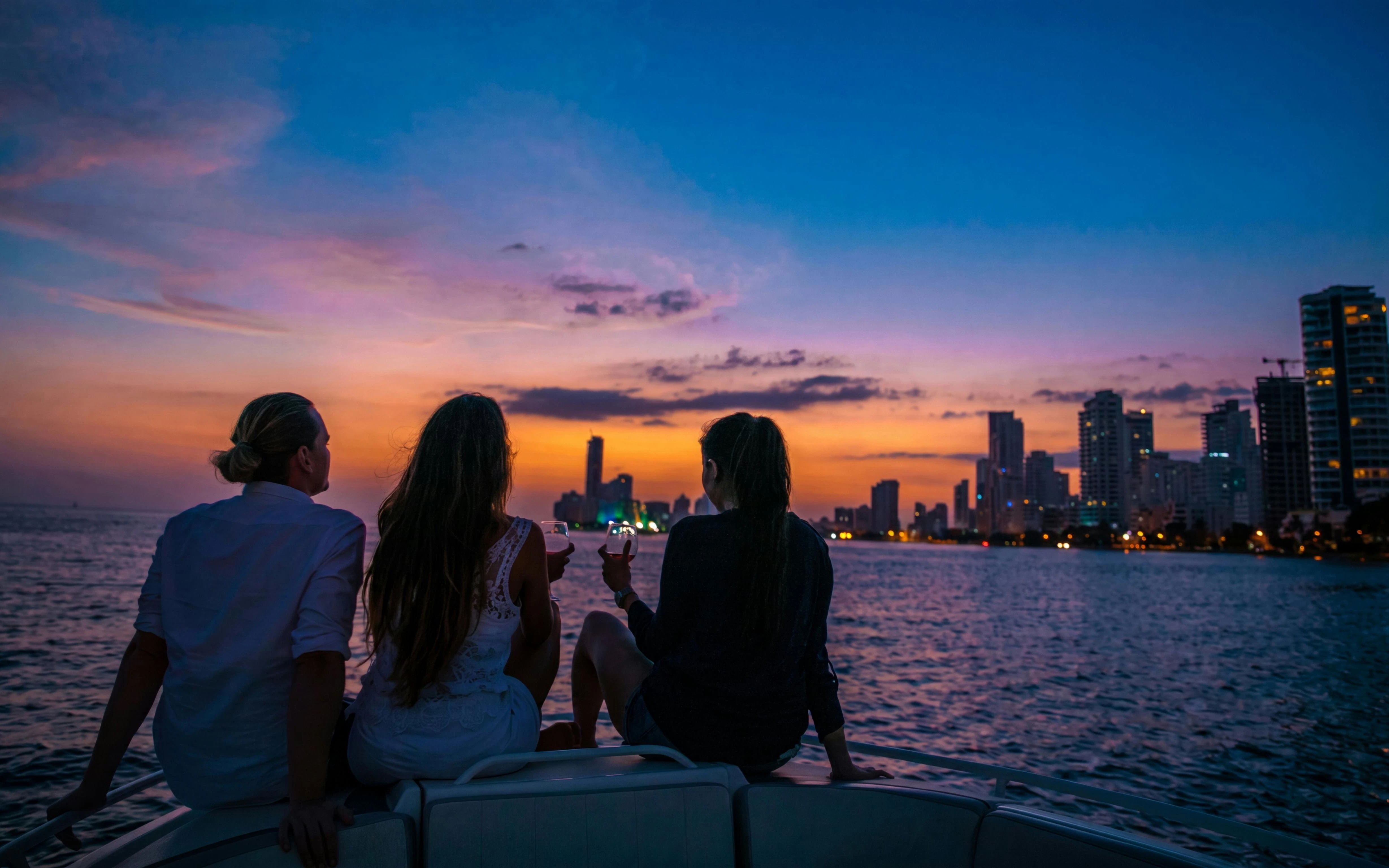 Tourists enjoying a sunset boat party in Cartagena's Bay with city skyline.