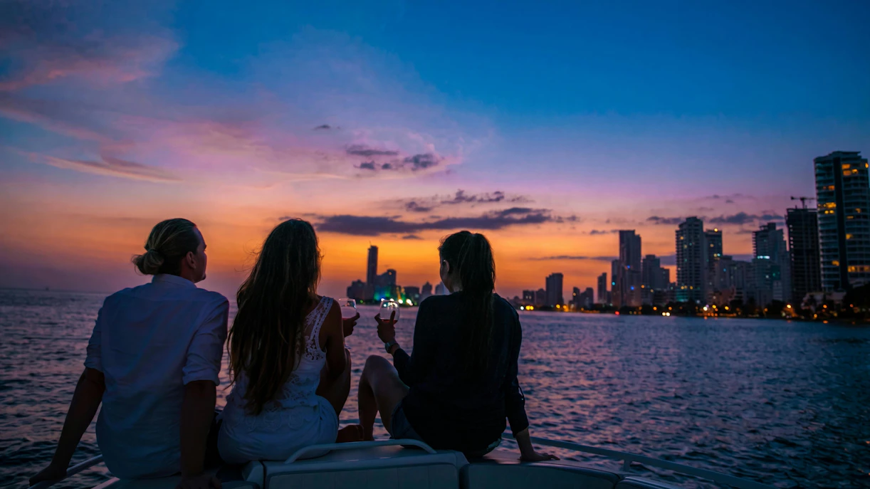 Tourists enjoying a sunset boat party in Cartagena's Bay with city skyline.
