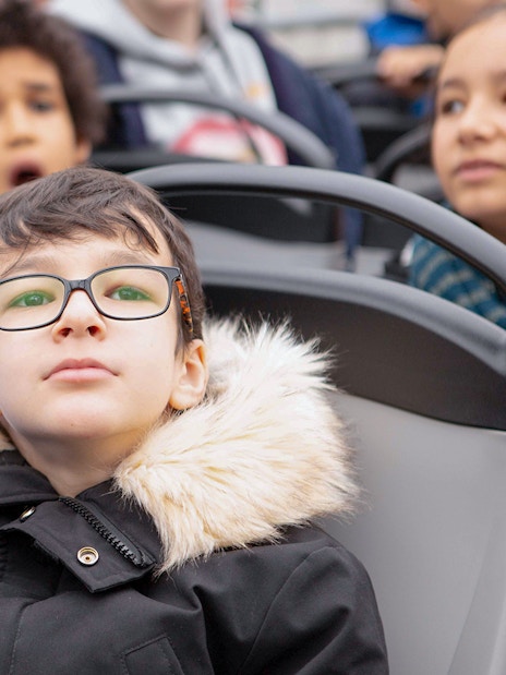 Child with glasses enjoying view on Tootbus tour in Paris.