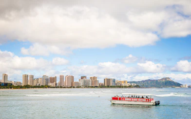 Glass-bottom boat on water with Honolulu skyline and Diamond Head in the background, Hawaii.