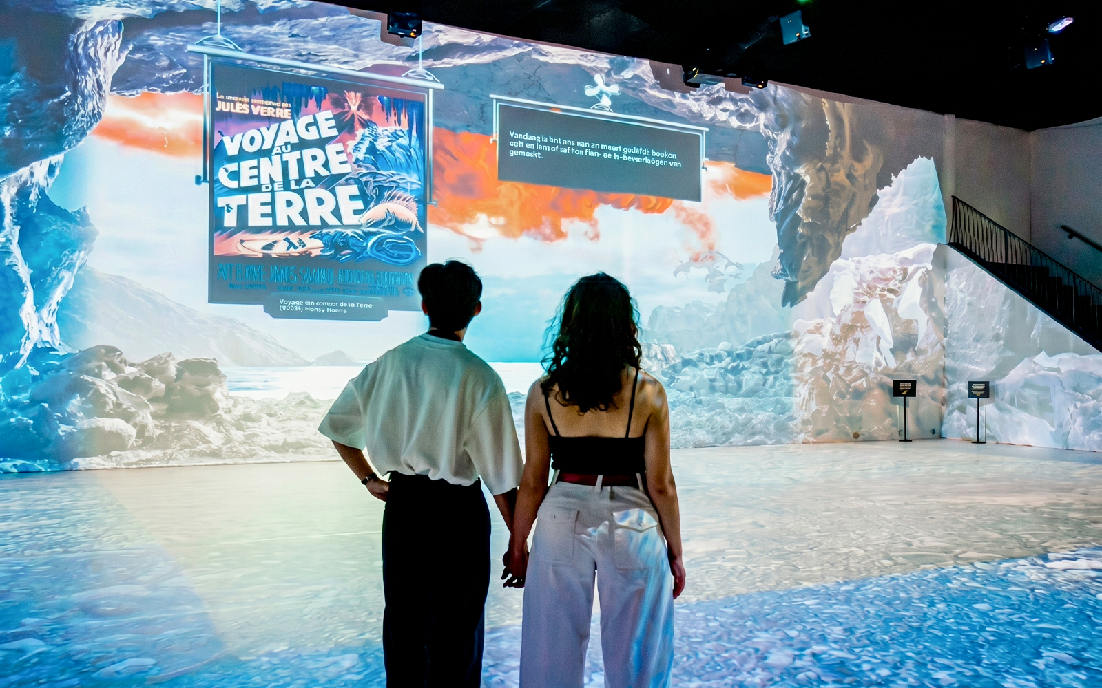 Couple viewing immersive Jules Verne exhibit, "Voyage au Centre de la Terre," with vivid cave projections.