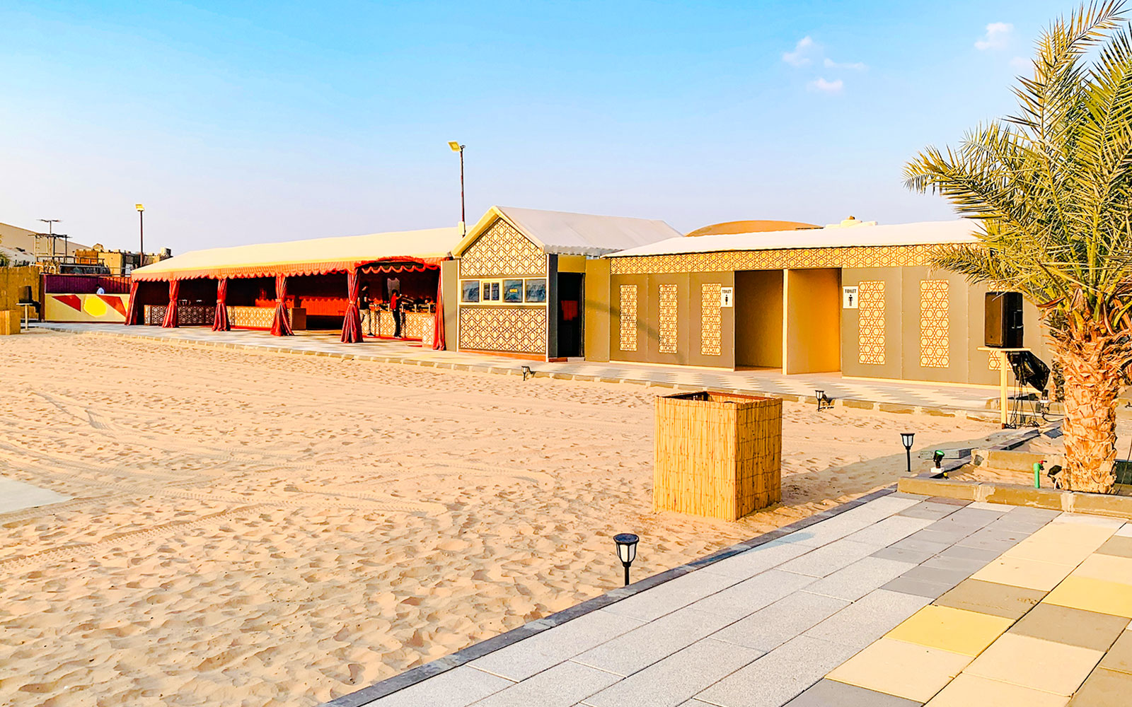 Desert camp site with traditional tents and palm tree in Abu Dhabi.