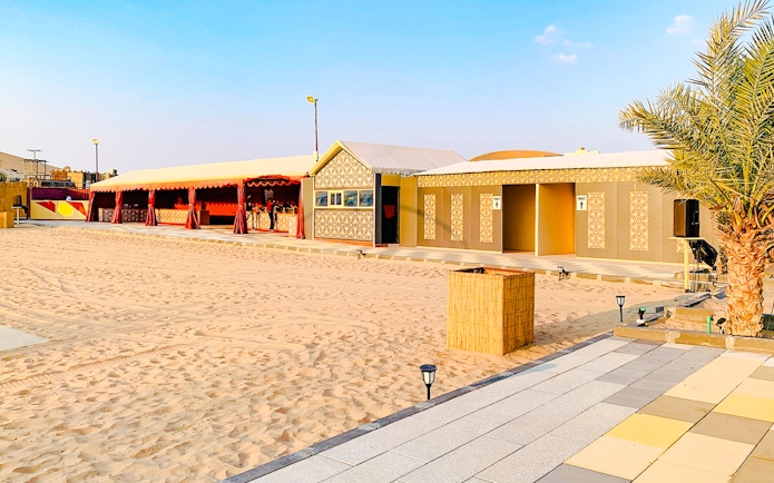 Desert camp site with traditional tents and palm tree in Abu Dhabi.