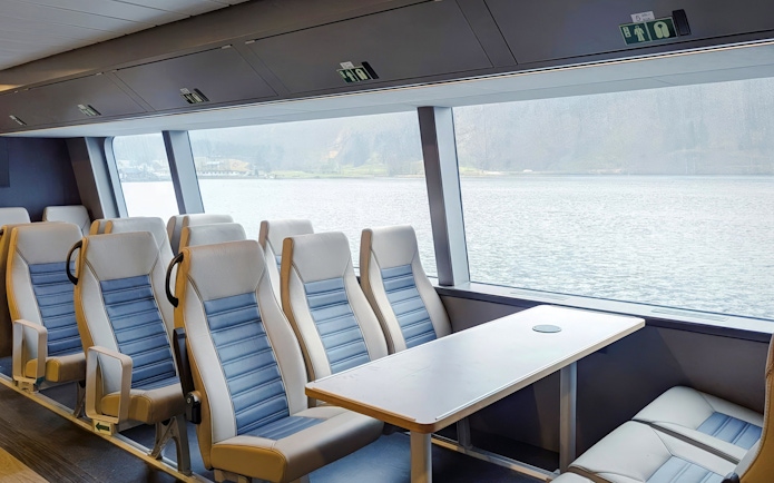 Cruise ship seating with large windows overlooking Geiranger Fjord.