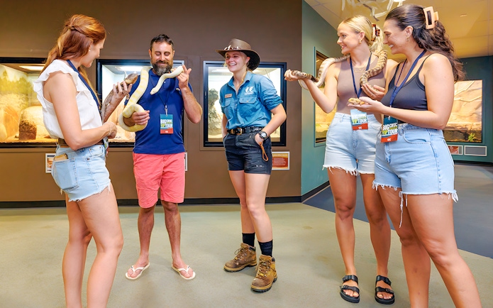 Guests holding snakes at Crocosaurus Cove exhibit.