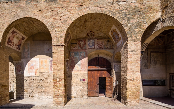 Siena Cathedral frescoes and arches with open wooden door, Italy.