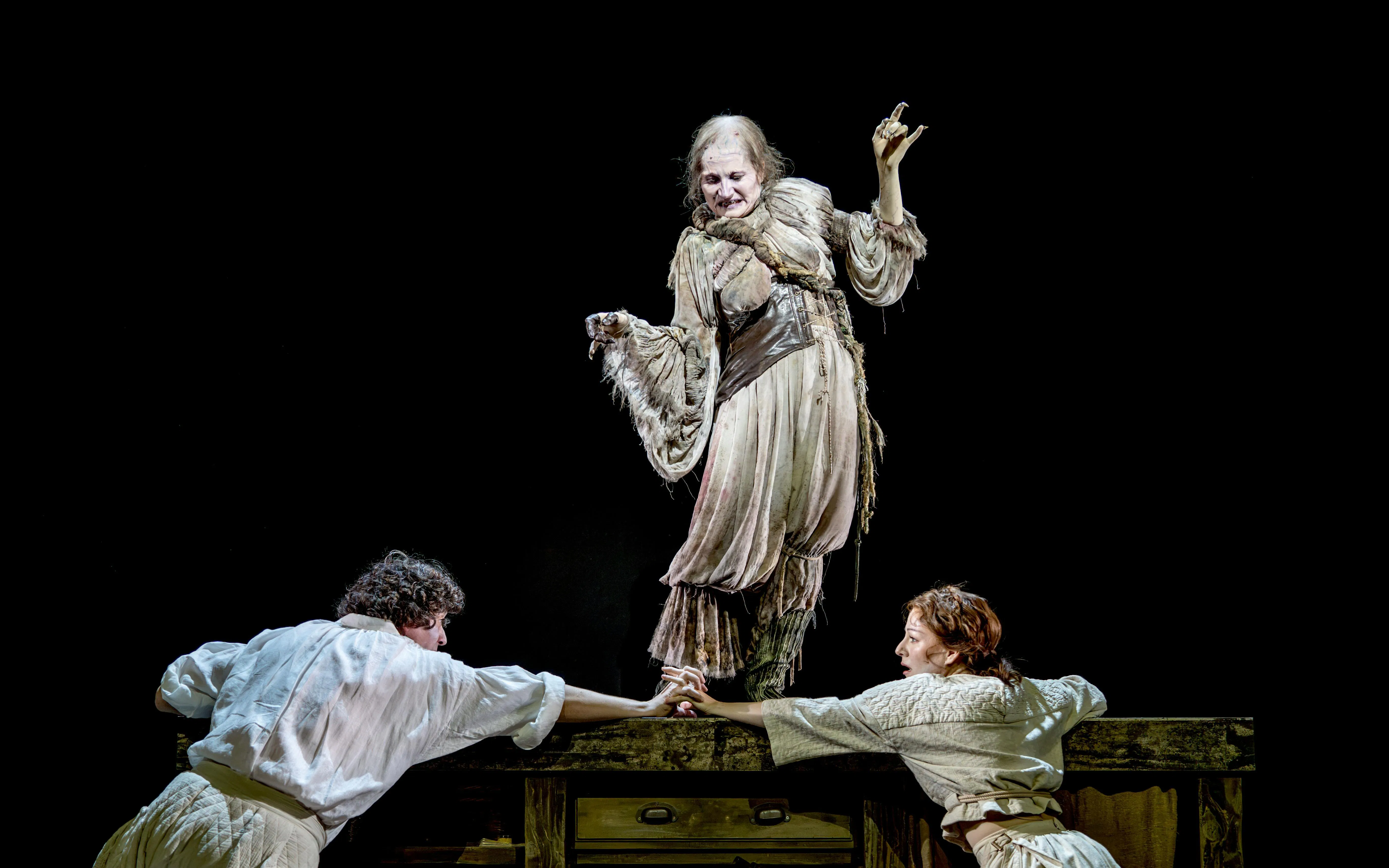 Actors performing a scene from "Into the Woods" with a witch character on stage.