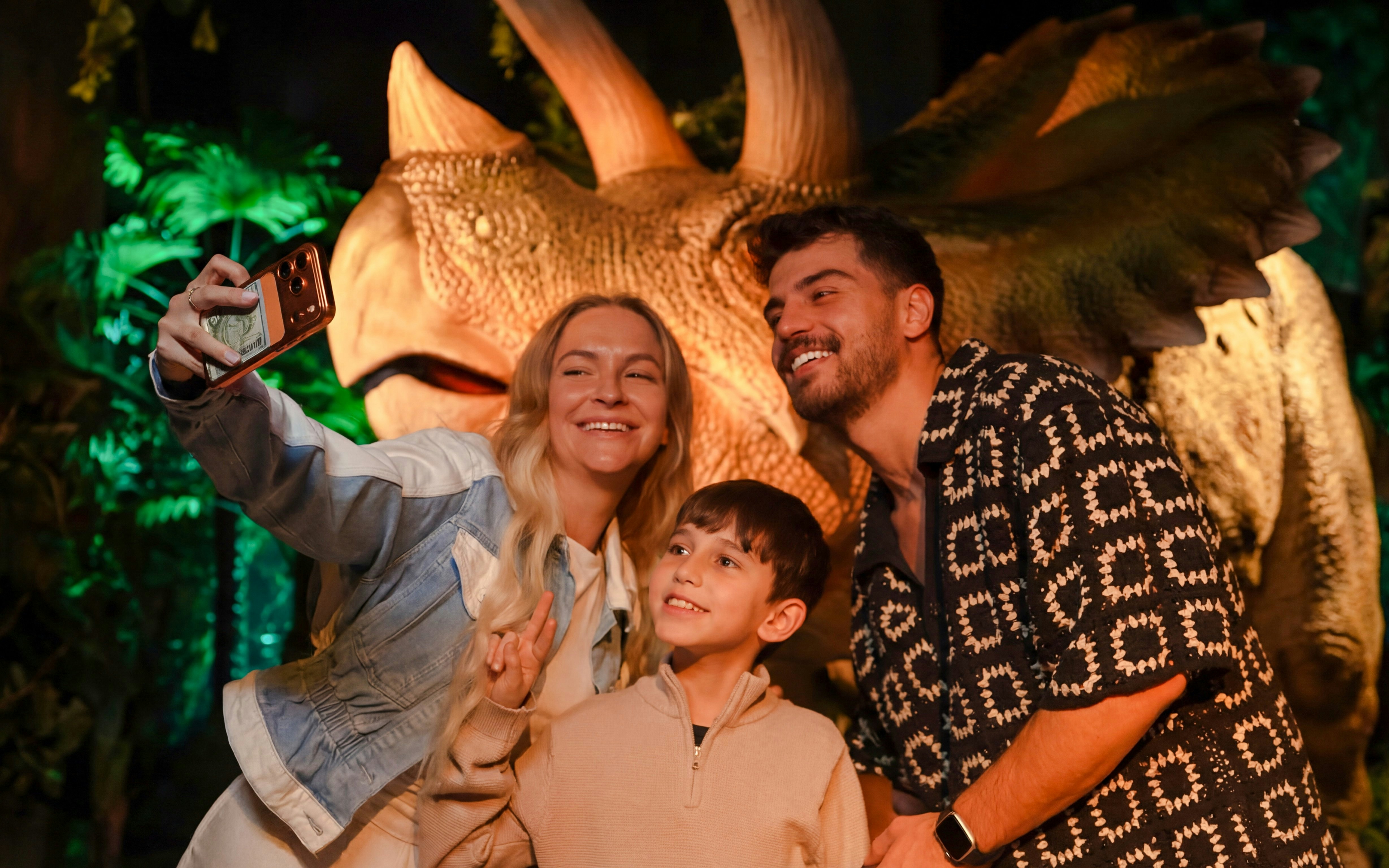 Family taking a selfie with a dinosaur exhibit at the immersive VR experience.