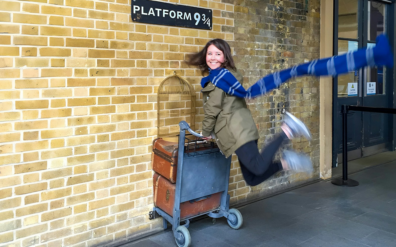 Person posing with luggage cart at Platform 9 ¾, King's Cross Station, London.