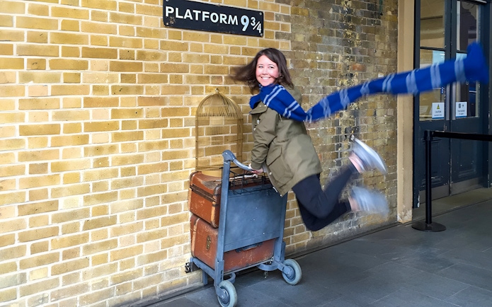 Person posing with luggage cart at Platform 9 ¾, King's Cross Station, London.