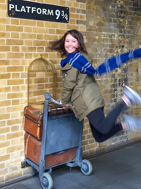 Person posing with luggage cart at Platform 9 ¾, King's Cross Station, London.