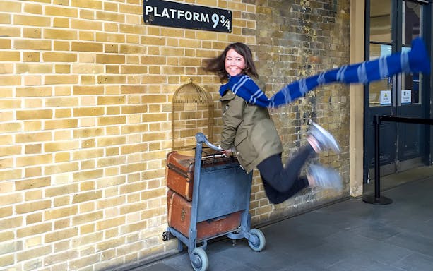 Person posing with luggage cart at Platform 9 ¾, King's Cross Station, London.