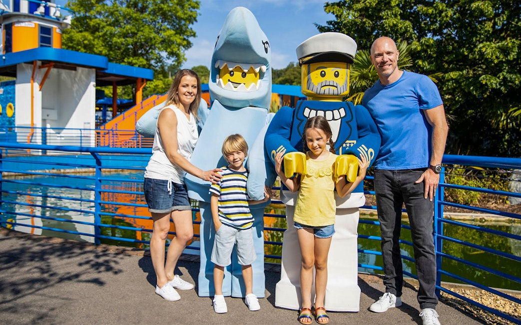 Family posing with LEGO shark and sailor figures at LEGOLAND® Windsor Resort.