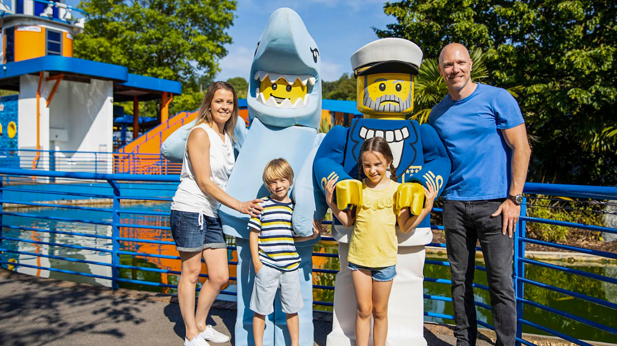 Family posing with LEGO shark and sailor figures at LEGOLAND® Windsor Resort.