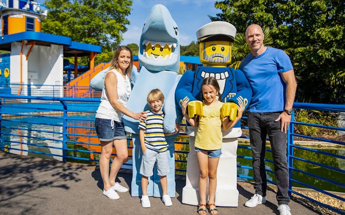 Family posing with LEGO shark and sailor figures at LEGOLAND® Windsor Resort.