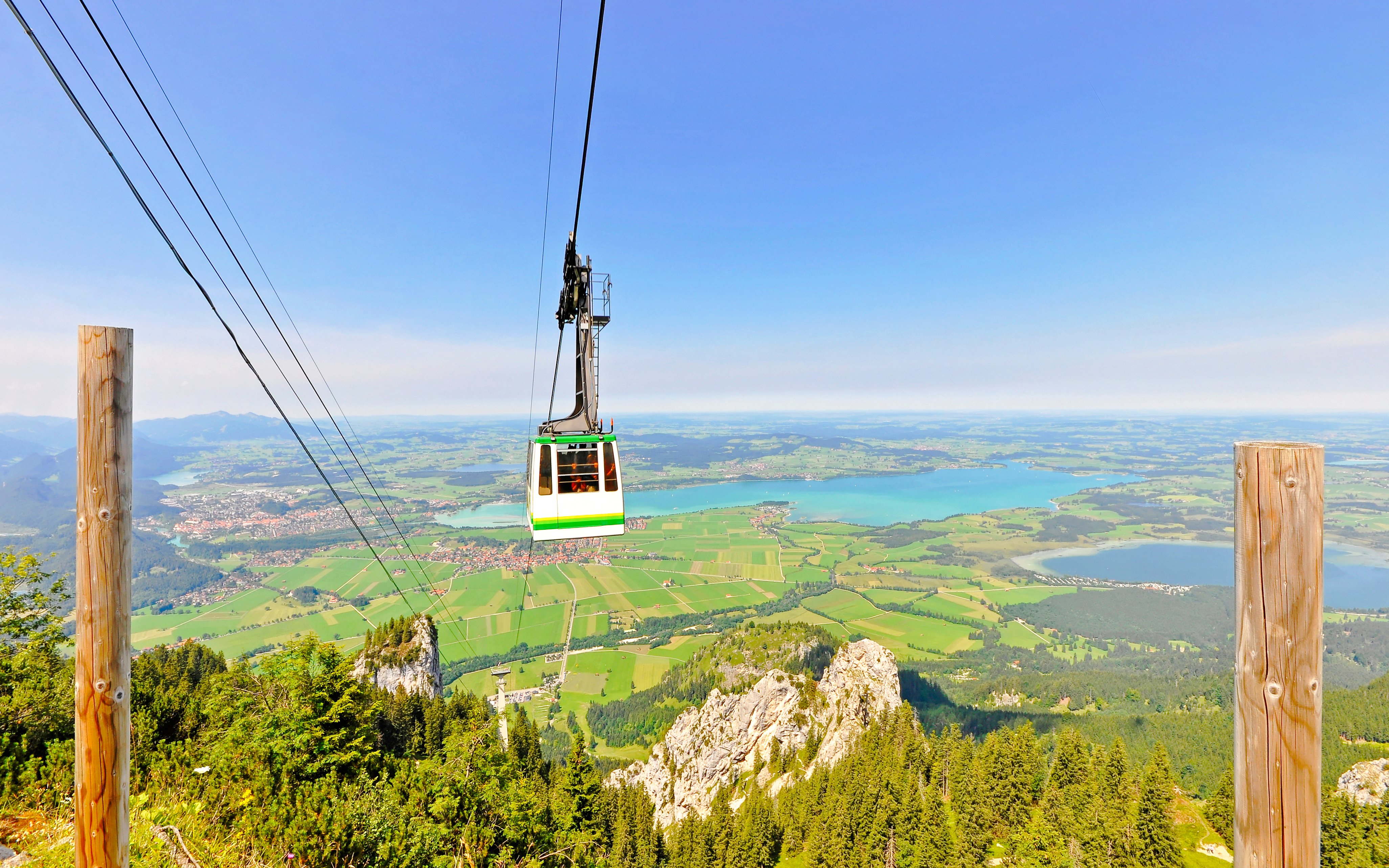 Tegelberg Cable Car ascending over lush landscape and lakes in Bavaria, Germany.