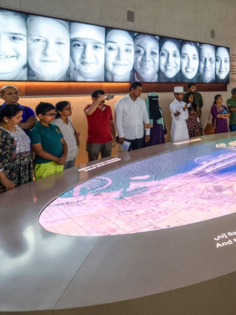 Tourist photographing interactive exhibit at Expo City Dubai with group observing.