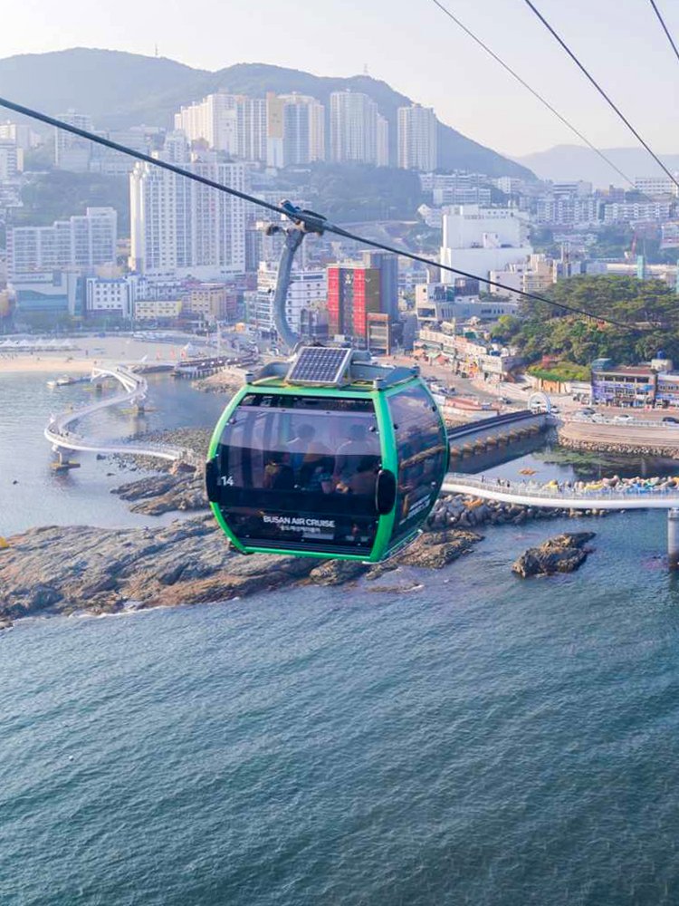 Cable car over Songdo Beach in Busan with cityscape and ocean view.