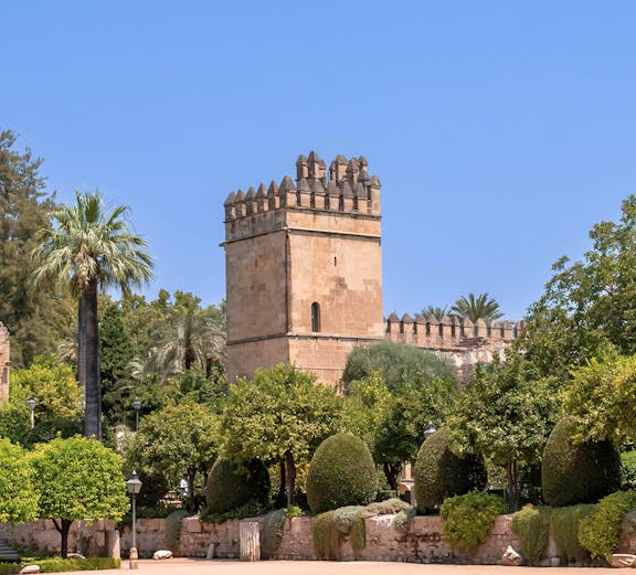 Alcazar of Cordoba tower and gardens under clear blue sky.