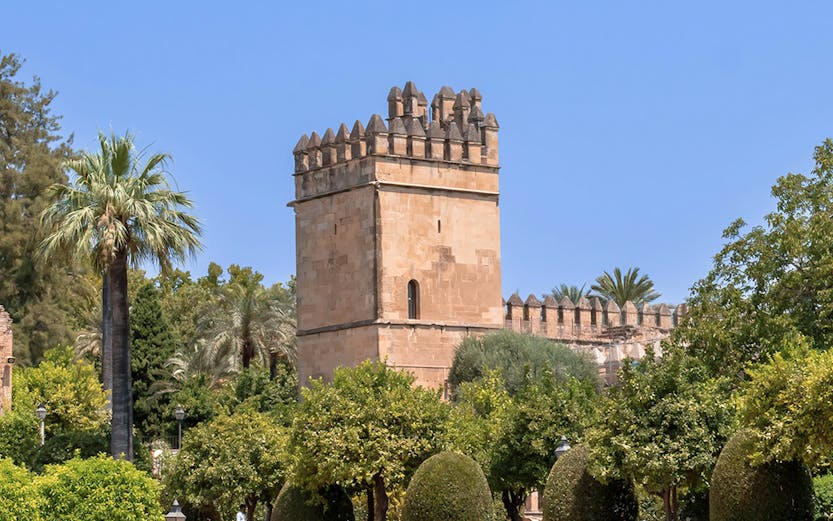 Alcazar of Cordoba tower and gardens under clear blue sky.