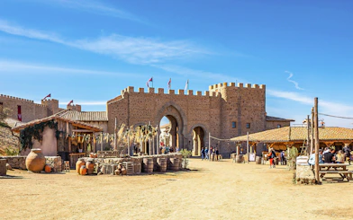 Medieval village scene at Puy du Fou España park with stone archway and visitors.