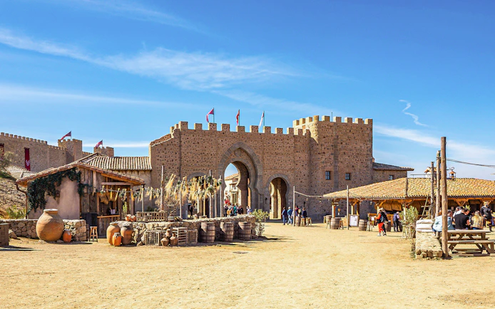 Medieval village scene at Puy du Fou España park with stone archway and visitors.