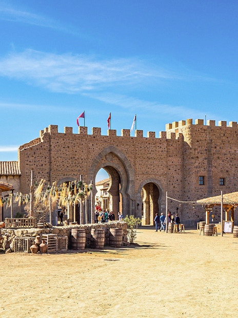 Medieval village scene at Puy du Fou España park with stone archway and visitors.