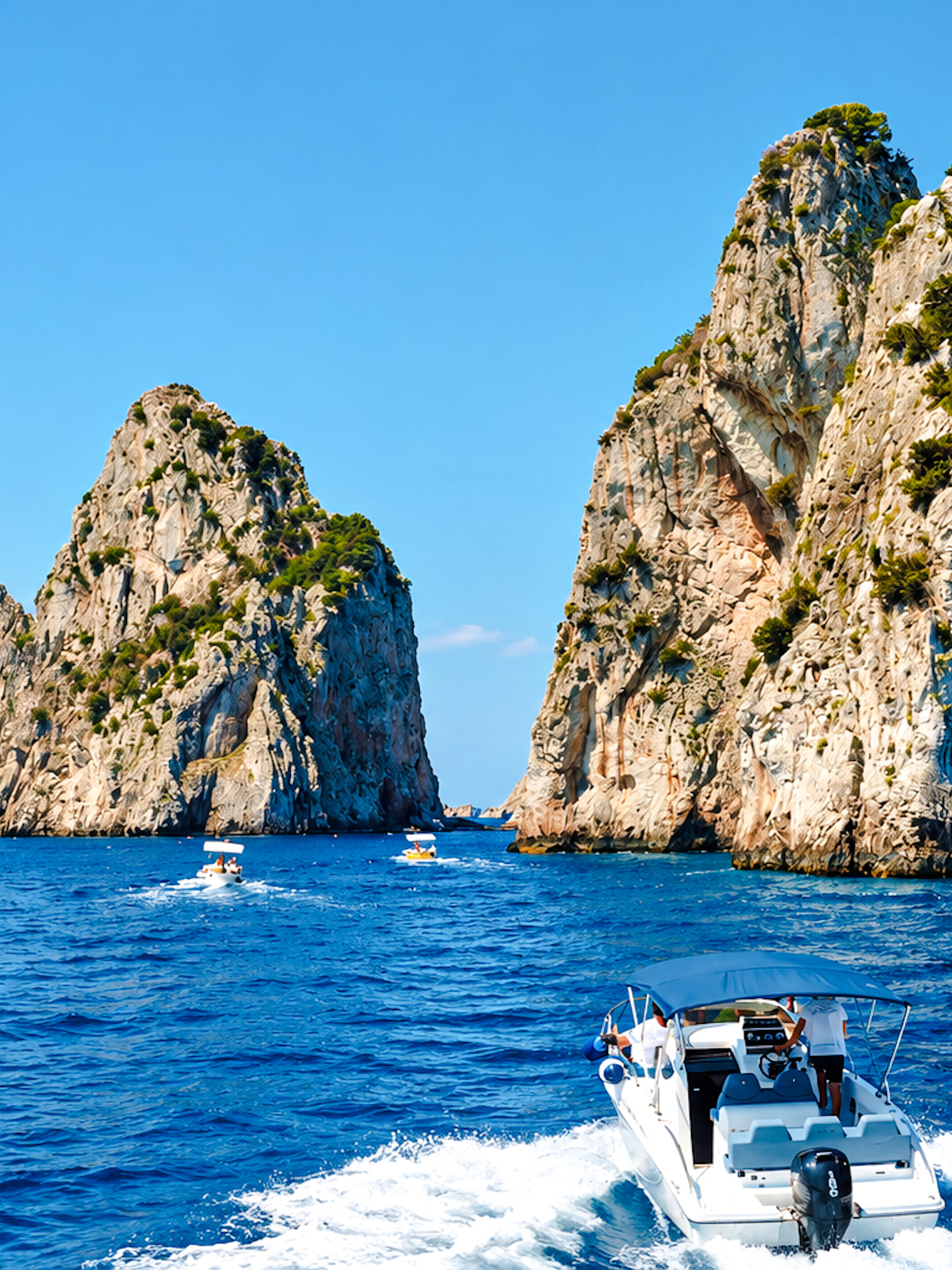 Boat approaching Faraglioni rock formations, Capri, Italy.