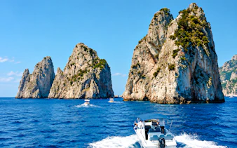 Boat approaching Faraglioni rock formations, Capri, Italy.