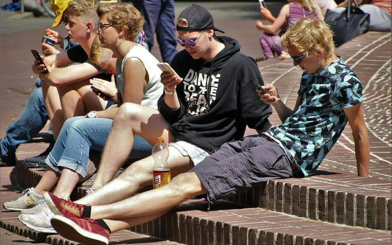 People sitting on brick steps using smartphones during a self-guided city exploration game in New Orleans.