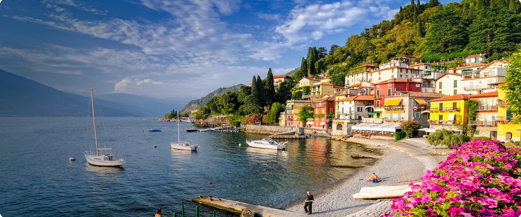 Colorful houses and boats along Lake Como shoreline, Italy.