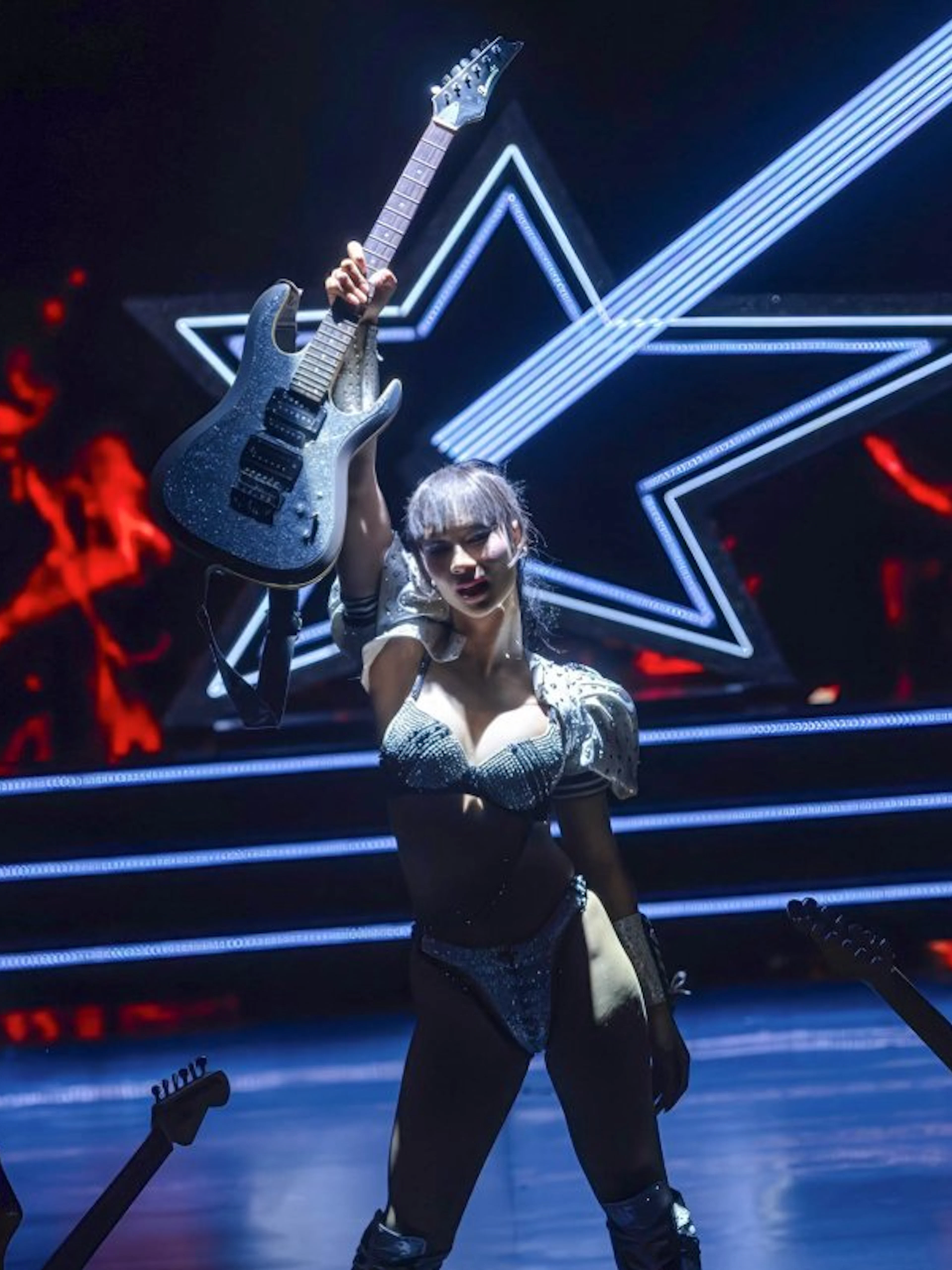 Performer holding guitar on stage at Calypso Cabaret, Bangkok.